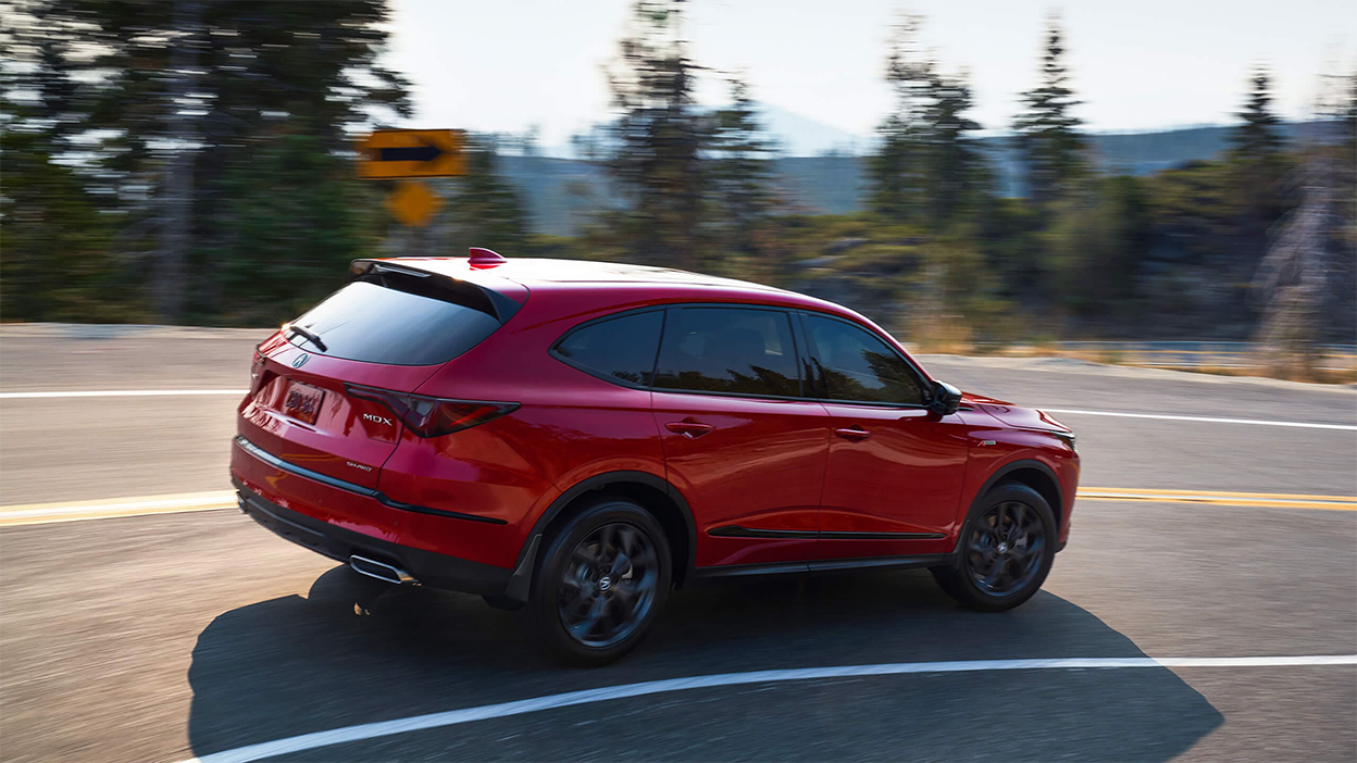 MDX rouge qui prend un virage en pleine nature.