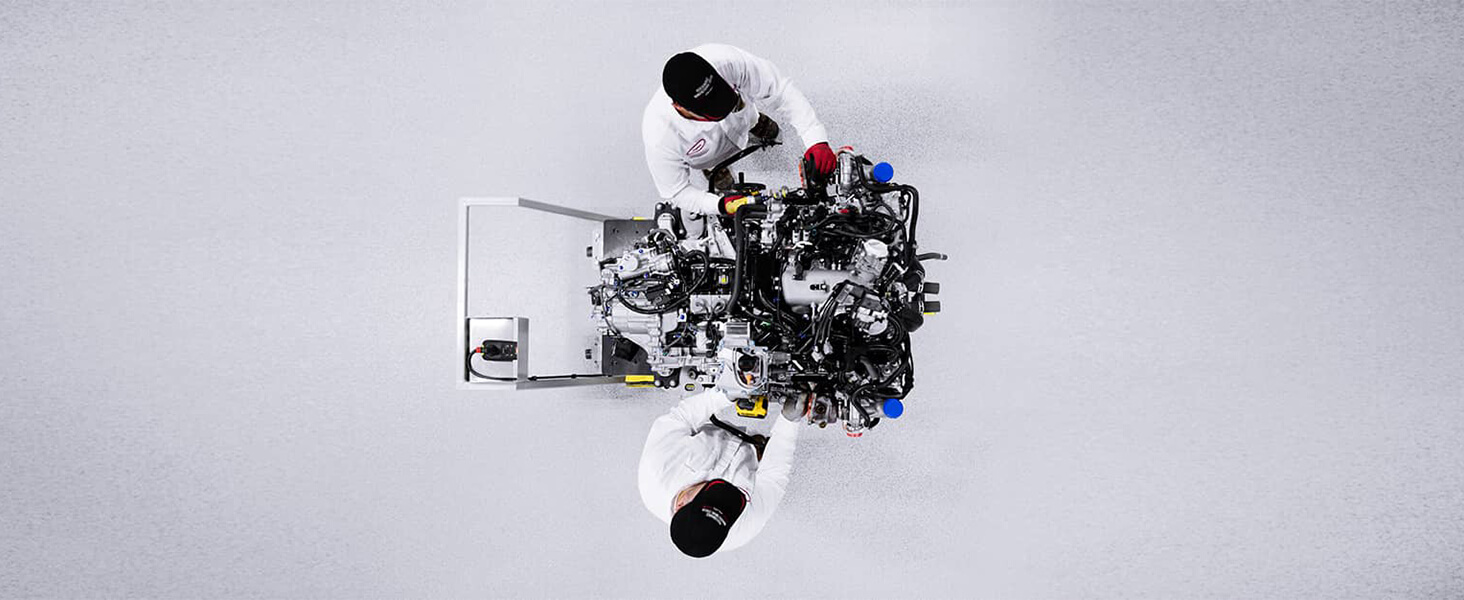 Overhead shot of two Acura engineers in whitespace, working on a futuristic engine. Vue aérienne de deux ingénieurs Acura dans une salle blanche qui travaillent sur un moteur futuriste.