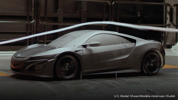 Driver side shot of a black Acura NSX Supercar in a testing garage facility. An air stream flows above as the car as it is put through a wind tunnel test. // Vue du côté conducteur d’une supervoiture Acura NSX noire dans le garage d’une installation d’essai. Un flux d’air circule au-dessus du véhicule lors d’un essai en soufflerie.