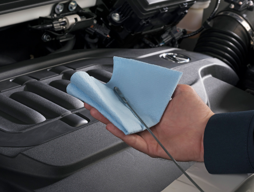 A certified Acura mechanic is cleaing the oil off of a engine dip-stick with a blue cloth. // Un mécanicien Acura certifié nettoie l'huile d'une jauge de moteur avec un chiffon bleu
